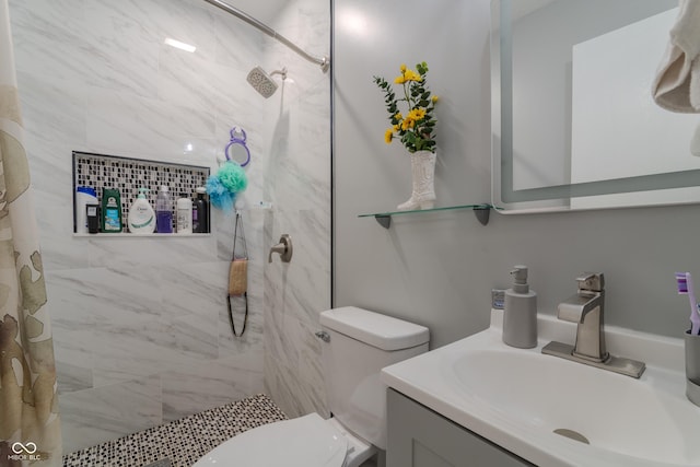 bathroom with a tile shower, toilet, and vanity