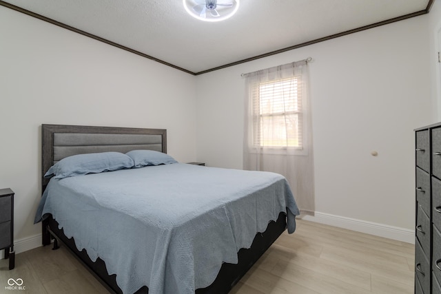 bedroom featuring light wood-type flooring, crown molding, and baseboards