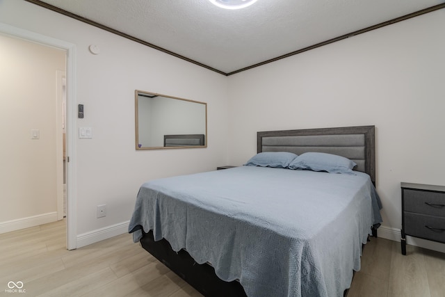 bedroom with baseboards, crown molding, and light wood-style flooring