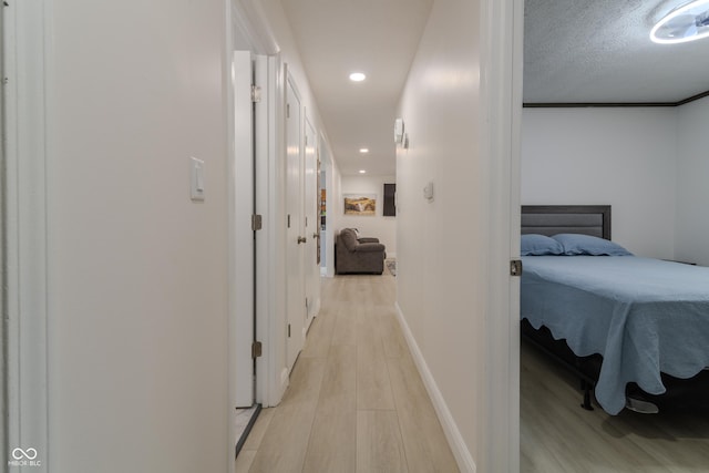 corridor with baseboards, recessed lighting, and light wood-type flooring