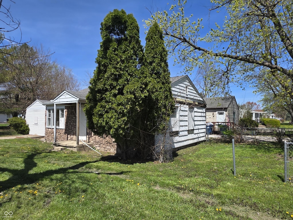 2950 Denison St, Indianapolis, IN 46241 - view of side of property featuring fence, an outbuilding, a yard, and stone siding