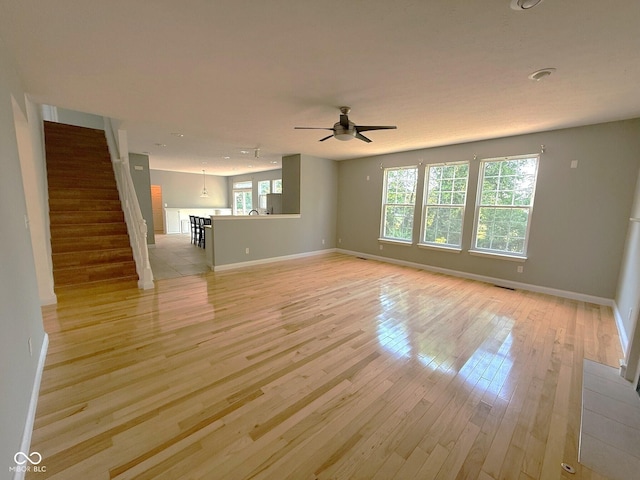 3724 Jonathan Rdg, Columbus, IN 47201 - unfurnished living room featuring light wood-type flooring, a ceiling fan, and stairway