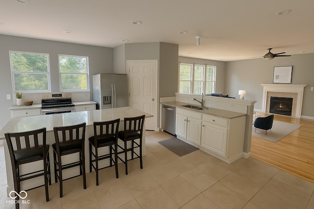3724 Jonathan Rdg, Columbus, IN 47201 - kitchen featuring stainless steel appliances, ceiling fan, white cabinetry, open floor plan, and a glass covered fireplace