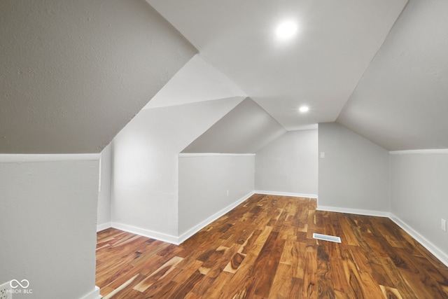 additional living space featuring baseboards, lofted ceiling, wood finished floors, and visible vents