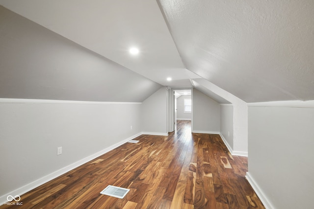 bonus room with baseboards, vaulted ceiling, dark wood finished floors, and visible vents