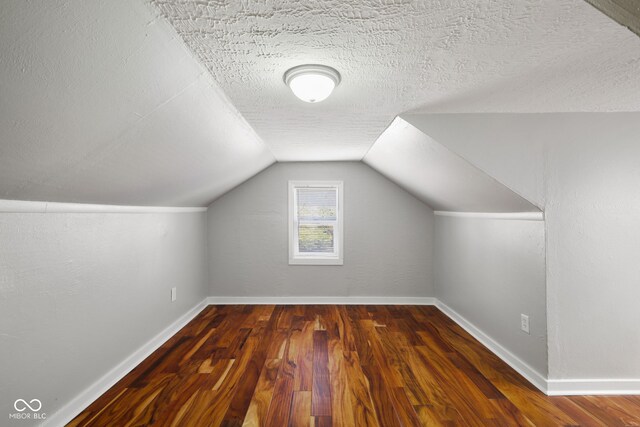 bonus room featuring baseboards, a textured ceiling, wood finished floors, and lofted ceiling
