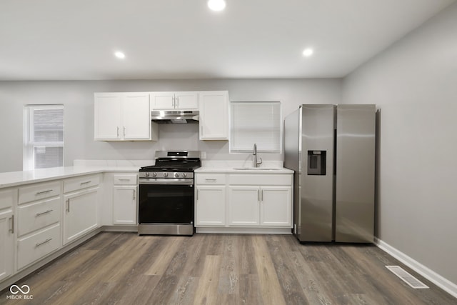 kitchen with white cabinets, a sink, stainless steel appliances, under cabinet range hood, and visible vents