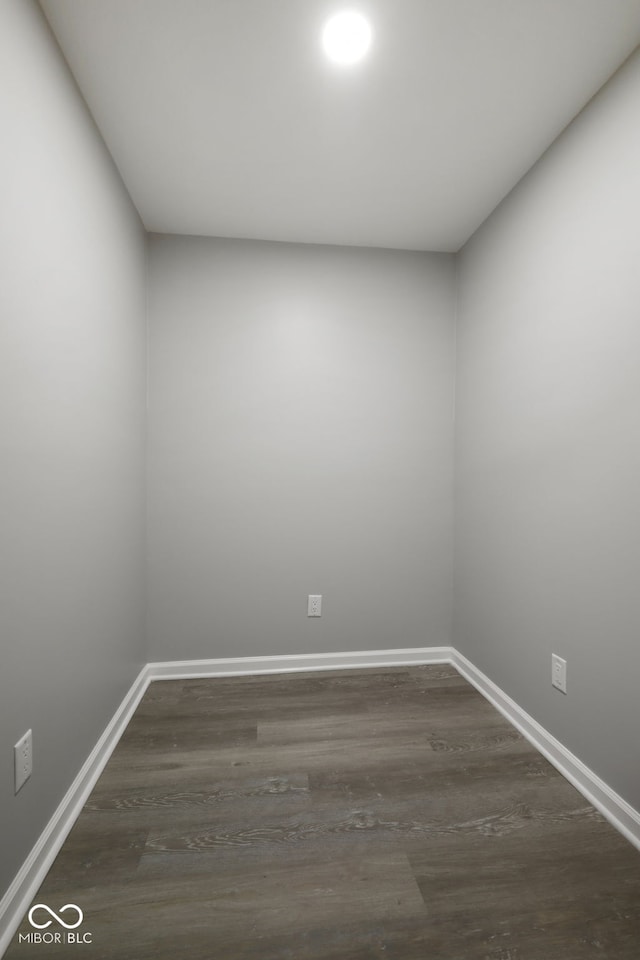 unfurnished room with baseboards and dark wood-style floors