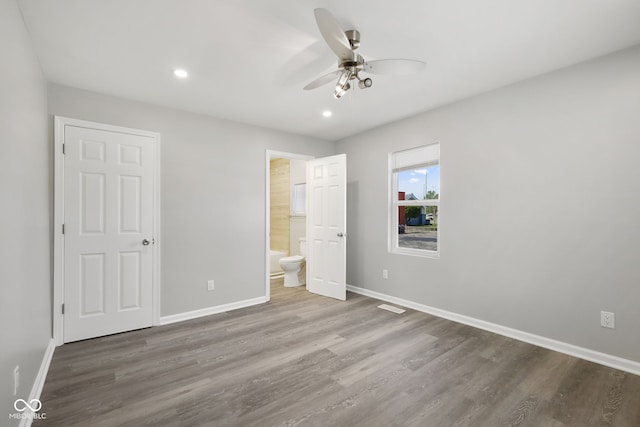 unfurnished bedroom with recessed lighting, baseboards, ensuite bath, and wood finished floors