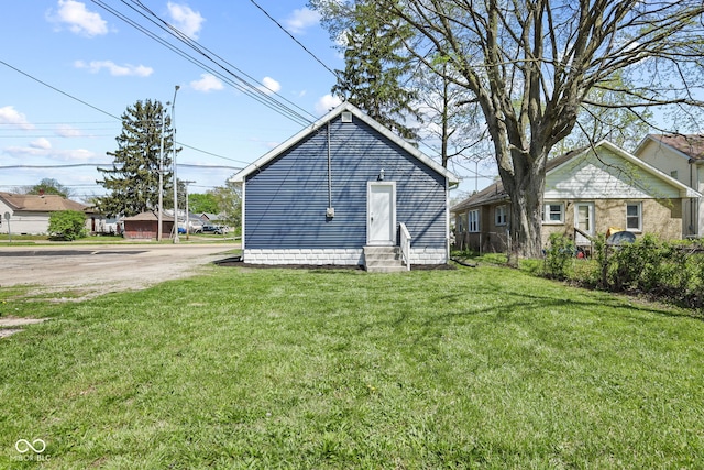 rear view of property featuring a lawn and entry steps
