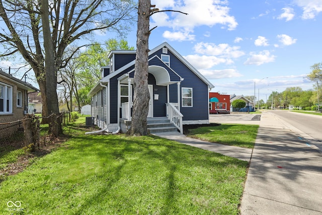 view of front facade featuring fence, cooling unit, and a front lawn