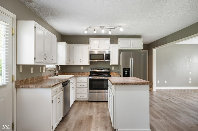 4786 N Mill Ct, Greenfield, IN 46140 - kitchen featuring stainless steel appliances, a sink, a center island, light wood-style flooring, and a textured ceiling