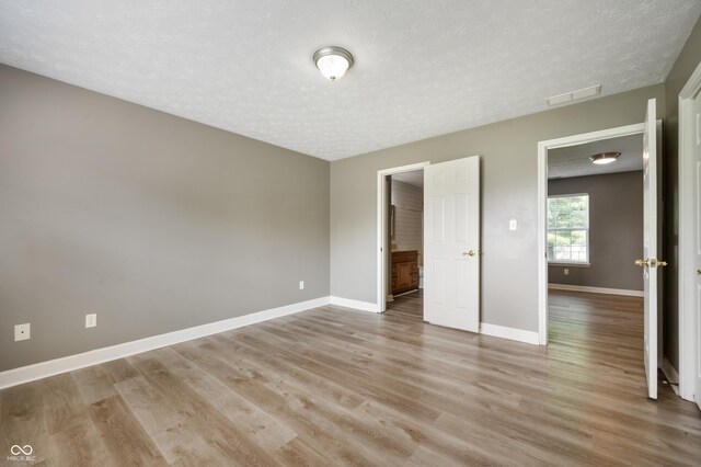 4786 N Mill Ct, Greenfield, IN 46140 - unfurnished bedroom featuring light wood finished floors, baseboards, and a textured ceiling