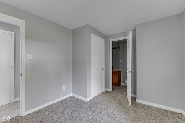 unfurnished bedroom with light carpet, ensuite bath, and baseboards