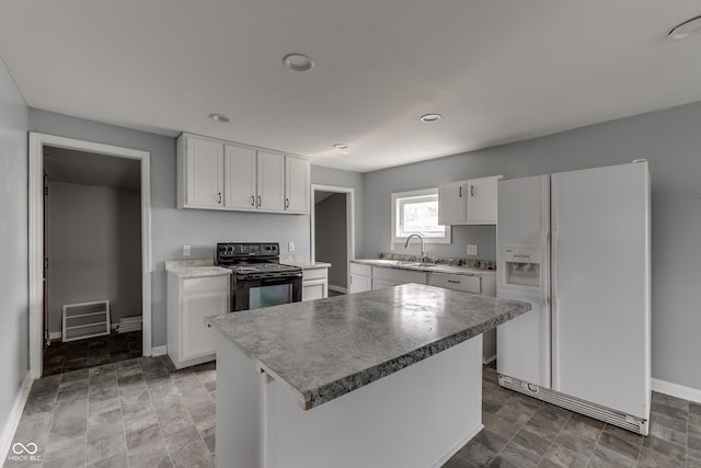kitchen featuring black electric range oven, a sink, white refrigerator with ice dispenser, baseboards, and white cabinetry