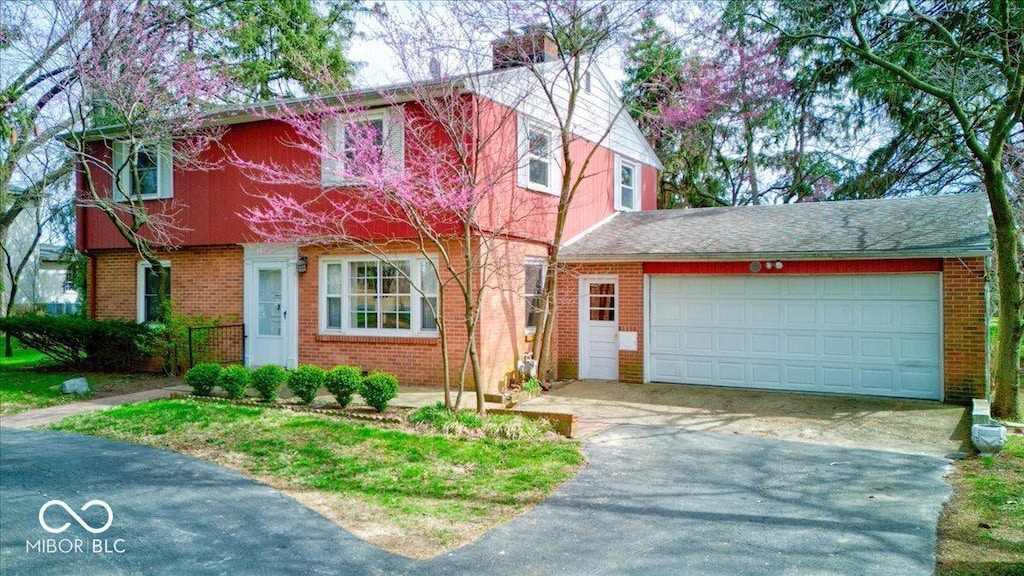 view of front of property featuring driveway, brick siding, and a chimney