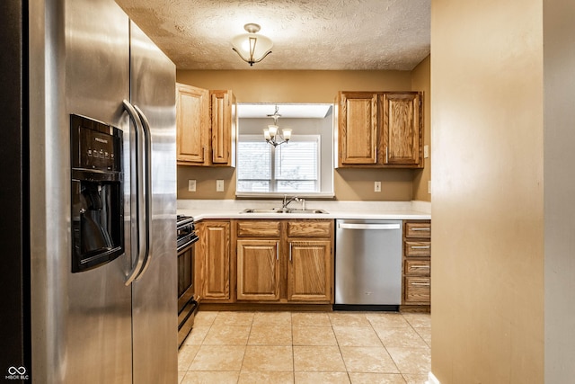 kitchen featuring a sink, a textured ceiling, appliances with stainless steel finishes, light countertops, and light tile patterned floors
