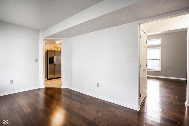 empty room with dark wood-type flooring and baseboards