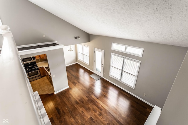 foyer entrance with dark wood finished floors, vaulted ceiling, visible vents, baseboards, and a textured ceiling