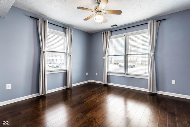 spare room featuring hardwood / wood-style floors, visible vents, a wealth of natural light, and a textured ceiling