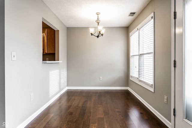 unfurnished dining area featuring an inviting chandelier, dark wood-style flooring, visible vents, and a healthy amount of sunlight