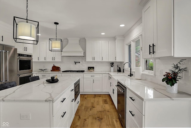 kitchen with recessed lighting, stainless steel appliances, a sink, a kitchen island, and custom range hood
