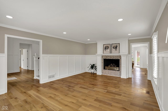 unfurnished living room featuring a decorative wall, visible vents, and light wood finished floors