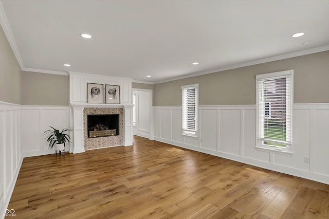unfurnished living room with plenty of natural light, a decorative wall, a wainscoted wall, and light wood-style flooring