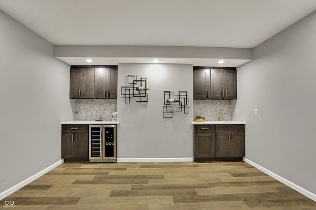 bar with decorative backsplash, wet bar, wine cooler, and light wood-type flooring