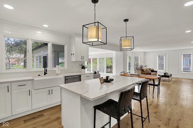 kitchen with white cabinets, dishwasher, a sink, and light wood-style floors