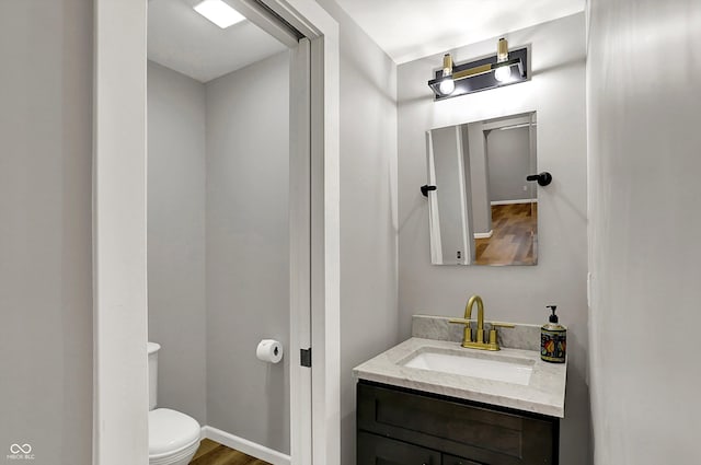 bathroom with wood finished floors, toilet, and vanity