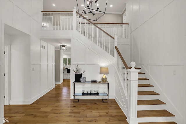 stairs with wood finished floors, a decorative wall, a towering ceiling, and visible vents