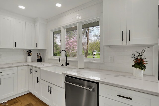 kitchen featuring white cabinets, decorative backsplash, stainless steel dishwasher, and a sink