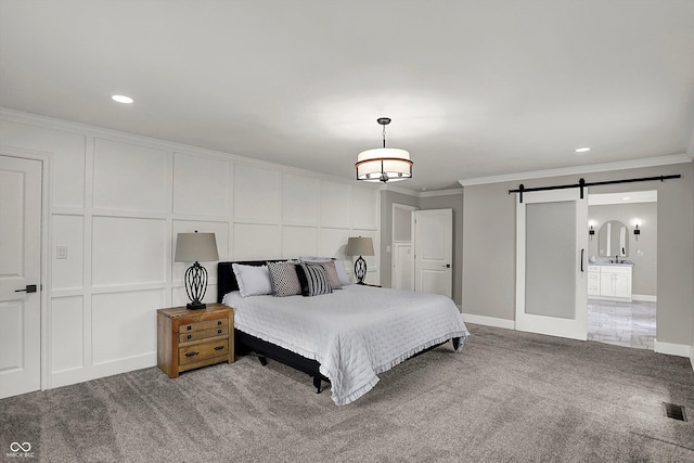 bedroom with a barn door, carpet floors, baseboards, ornamental molding, and visible vents