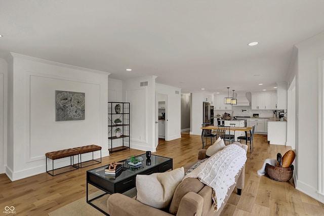 living area featuring baseboards, visible vents, light wood finished floors, and recessed lighting