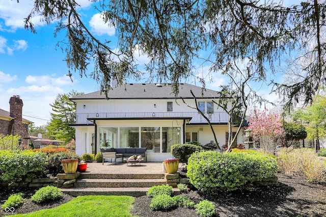 rear view of property with outdoor lounge area, a patio, a balcony, and a shingled roof