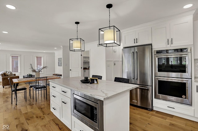 kitchen with white cabinets, light wood-style flooring, appliances with stainless steel finishes, and a center island