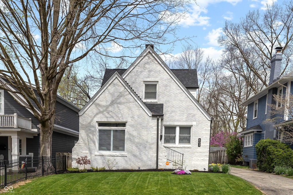 back of house with fence, a lawn, brick siding, and roof with shingles