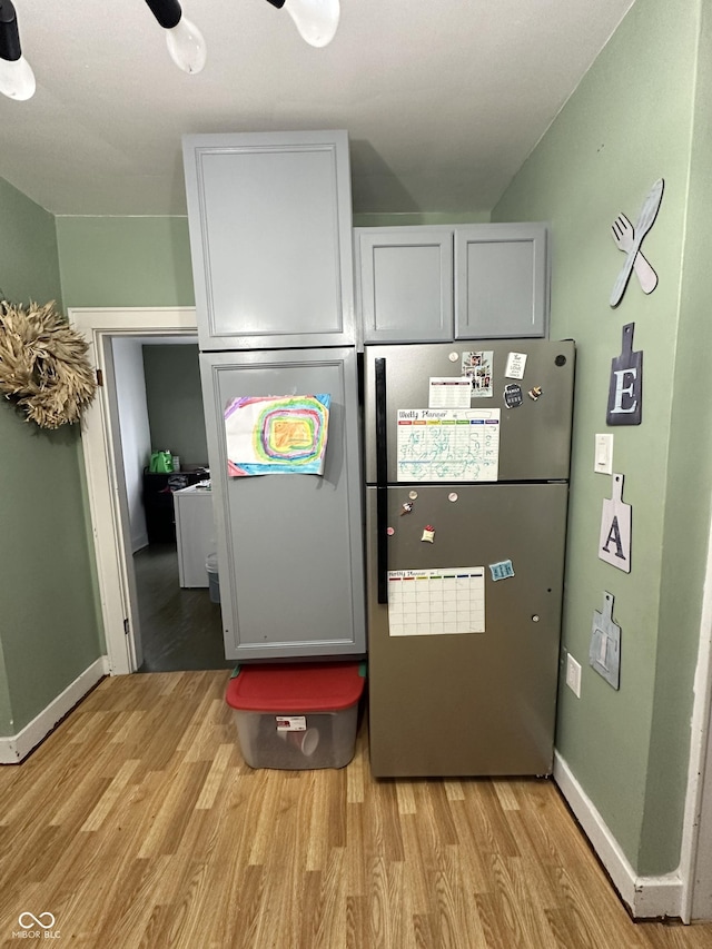 kitchen featuring light wood-type flooring, baseboards, and freestanding refrigerator