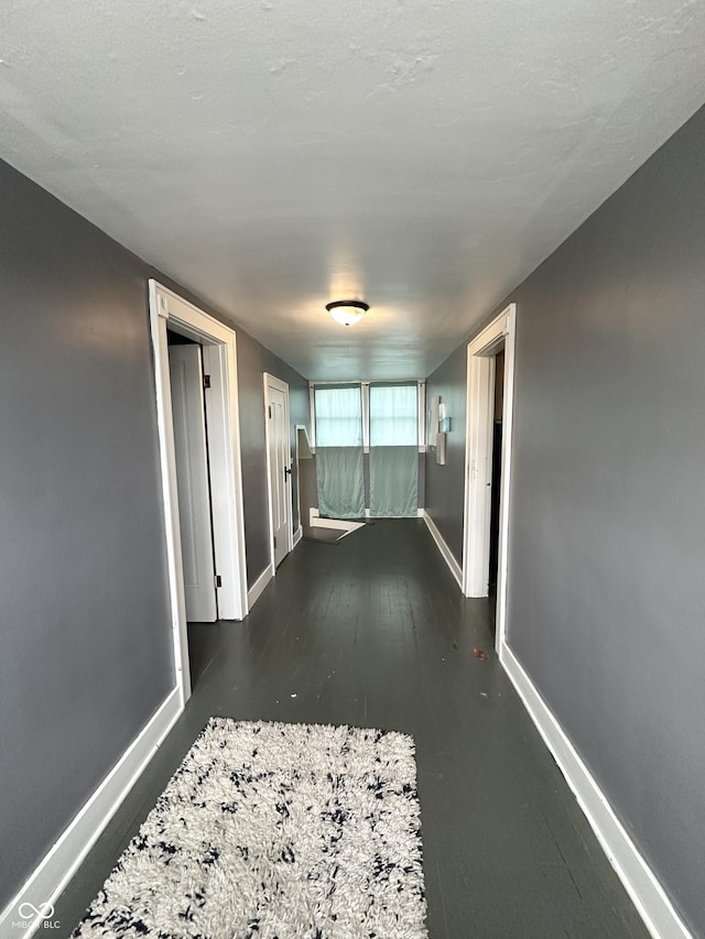 corridor with baseboards and wood finished floors