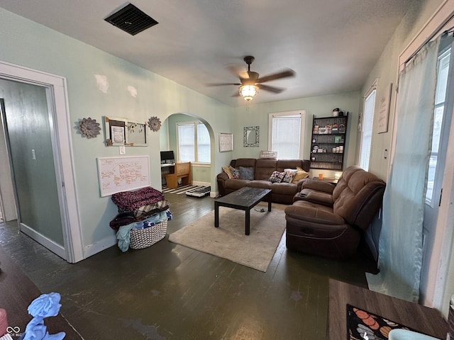 living area featuring baseboards, a ceiling fan, visible vents, arched walkways, and wood finished floors