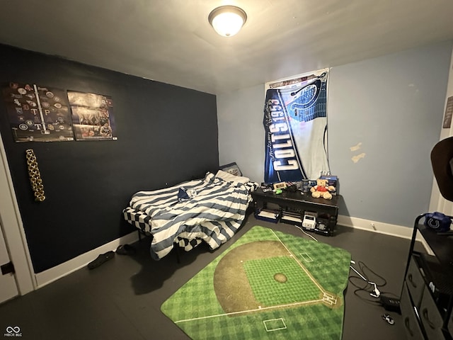 bedroom featuring concrete flooring and baseboards
