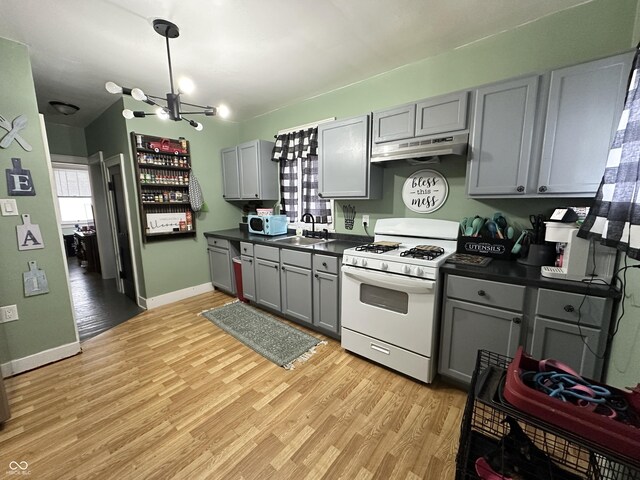 kitchen with gray cabinets, light wood-style flooring, dark countertops, and white appliances