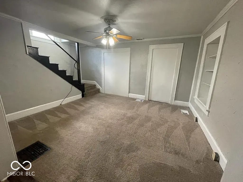 800 W Lindweth Pl, Muncie, IN 47303 - unfurnished living room featuring ceiling fan, baseboards, carpet flooring, and stairway