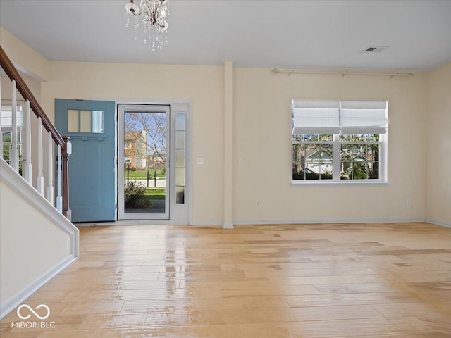entrance foyer featuring a chandelier, stairs, plenty of natural light, and visible vents