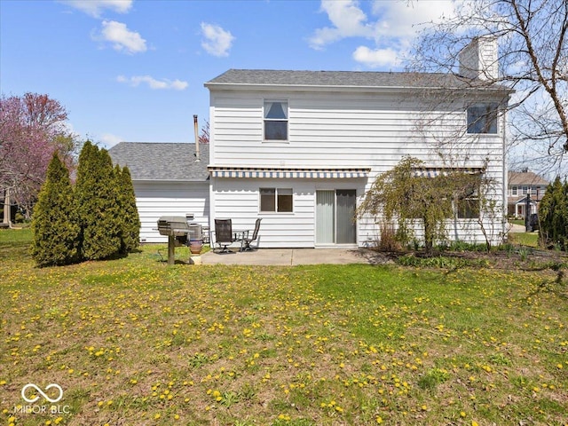 rear view of property featuring a chimney, a patio area, and a lawn