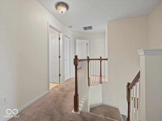 corridor featuring carpet flooring, visible vents, an upstairs landing, and baseboards