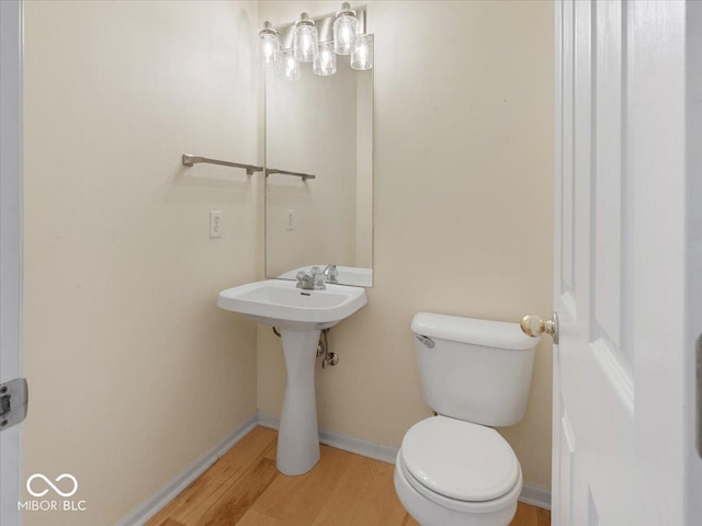bathroom featuring toilet, wood finished floors, and baseboards