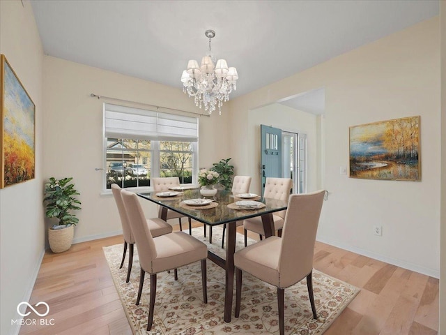 dining area featuring baseboards, a notable chandelier, and light wood-type flooring
