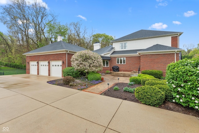traditional home featuring brick siding, driveway, and a chimney